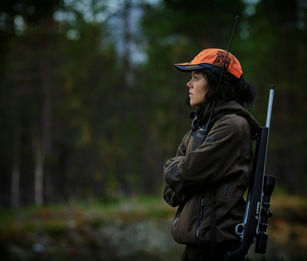 woman carrying hunting rifle in woods